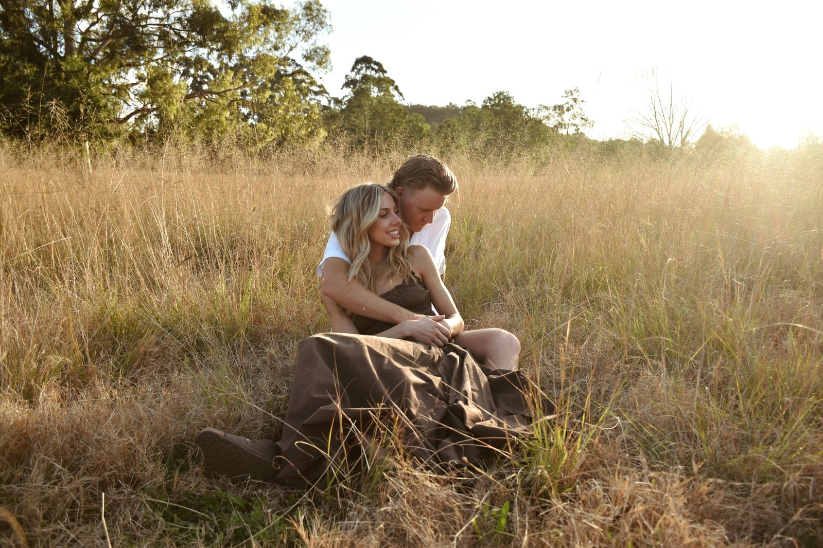 Couple embracing in a sunlit paddock