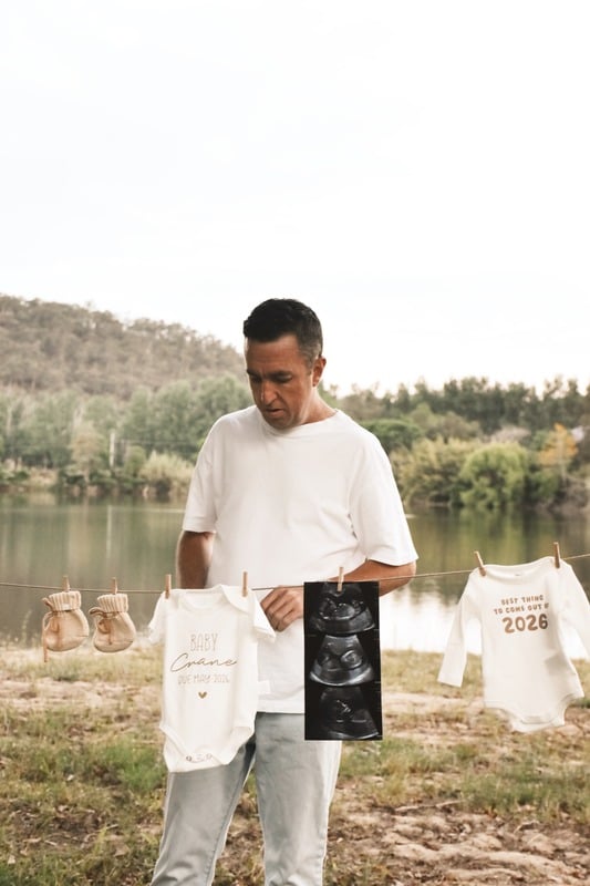 Father to be holding baby clothes and a scan