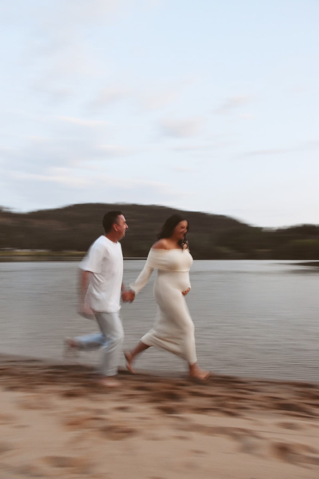 Expecting couple walking along the shoreline