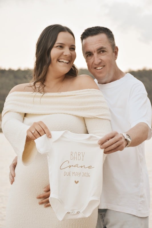 Parents holding a baby onesie by the lake