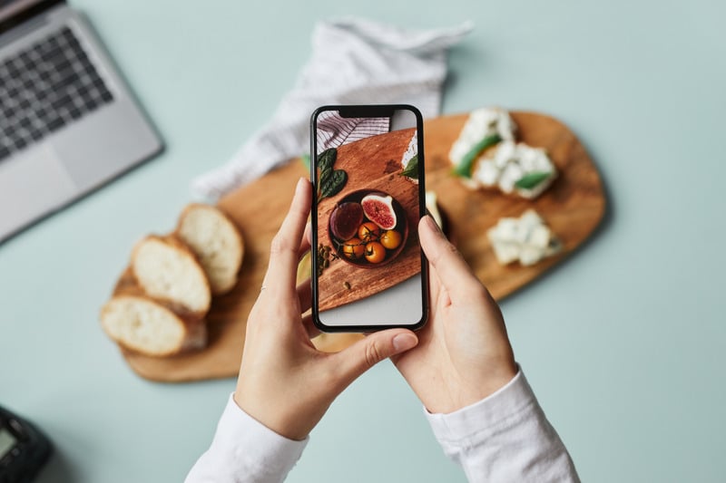 Hands photographing a styled food board with a phone